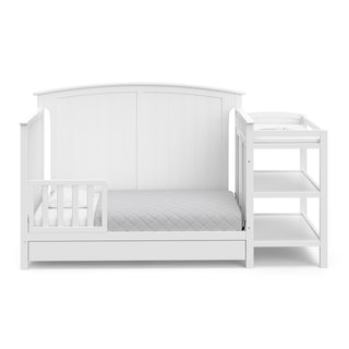 white crib and changer in toddler bed conversion with one toddler safety guardrail