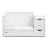 White crib and changer with drawer in toddler bed conversion with one safety guardrail 