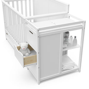 Close-up view of White crib and changer with open drawer