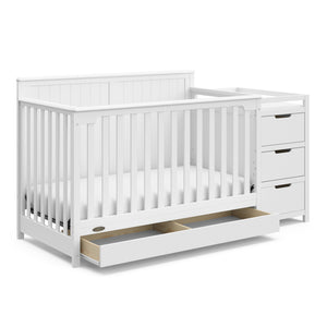 White crib and changer angled with open drawer