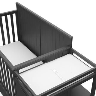 Close-up view of gray crib and changer with drawer