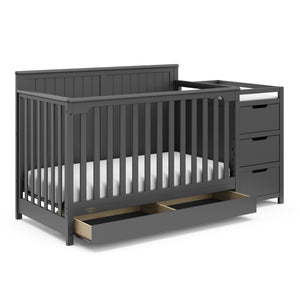 gray crib and changer angled with open drawer