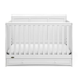 Front view of white crib with drawer