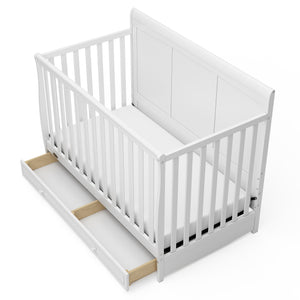 Bird's-eye view of a white crib with open drawer