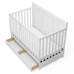 Bird's-eye view of a white crib with open drawer