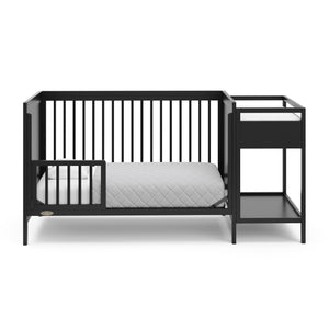 black crib in toddler bed conversion with one safety guardrail