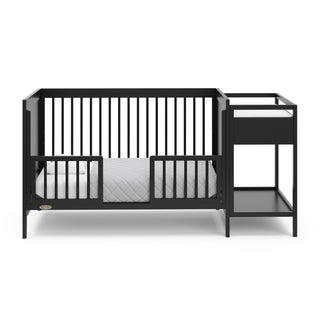 black crib in toddler bed conversion with two safety guardrails