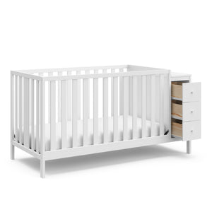 White crib with storage and open drawers angled