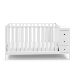 Front view of white crib with storage