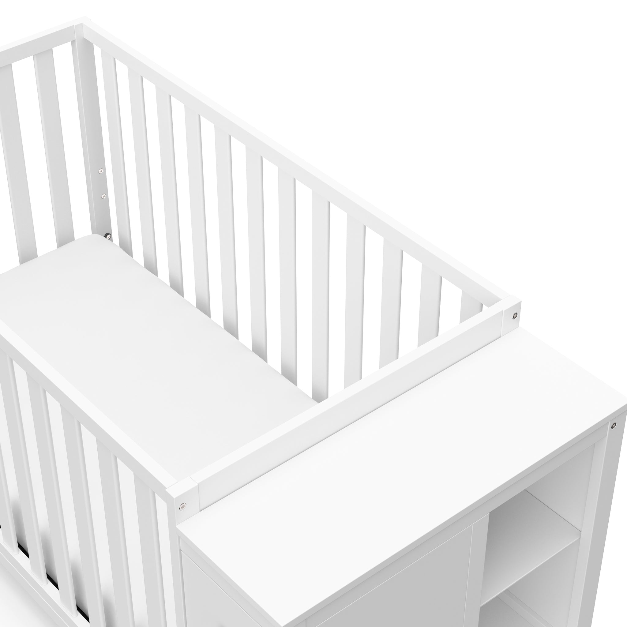 Close-up view of white crib with storage headboard
