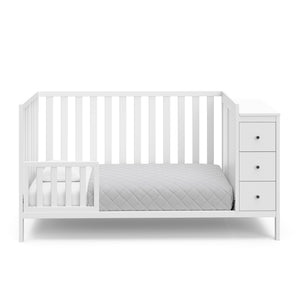 White crib with storage in toddler bed conversion with one safety guardrail