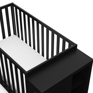 Close-up view of black crib with storage headboard