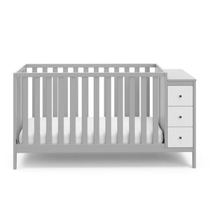 Front view of pebble gray and white crib with storage