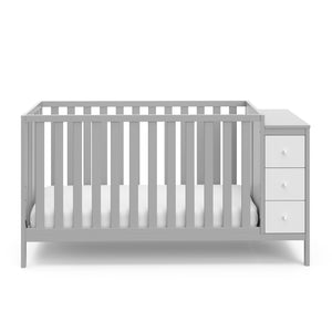 Front view of pebble gray and white crib with storage