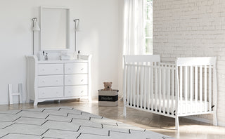 White crib in nursery with 6 drawer dresser