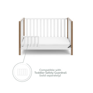 White crib with driftwood in toddler bed conversion with one safety guardrail graphic