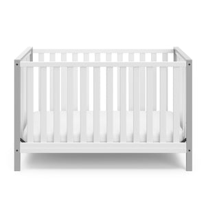 Front view of white crib with pebble gray