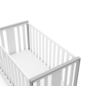 Close-up view of white with pebble gray crib's headboard
