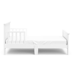 Side view of white toddler bed with guardrails