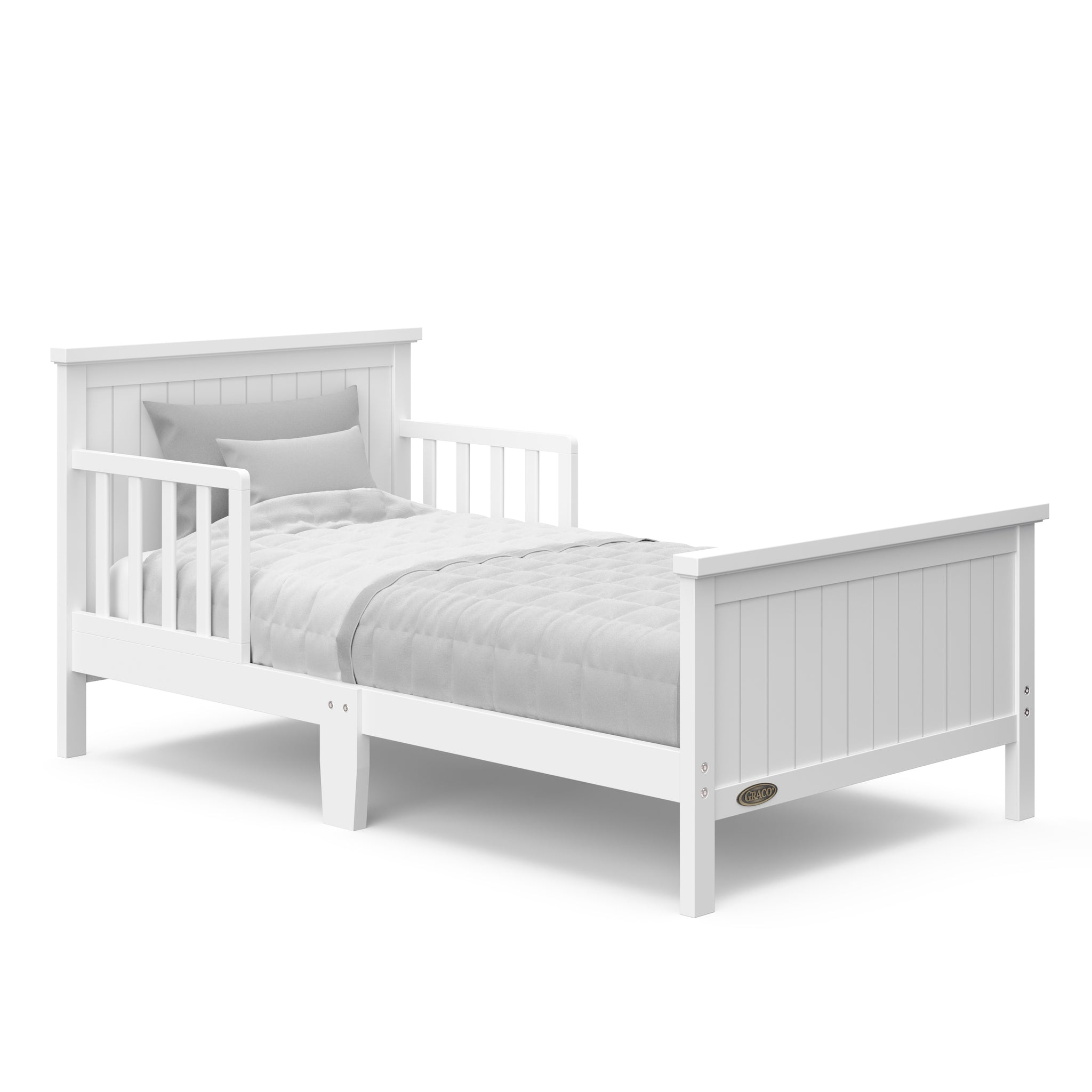 White toddler bed with guardrails angled with bedding