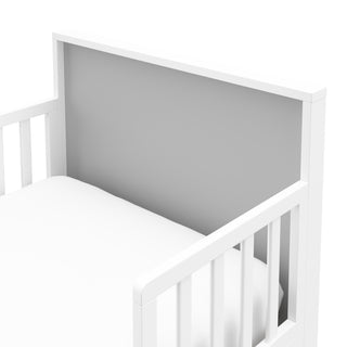 Close-up view of white with pebble gray toddler bed’s headboard 