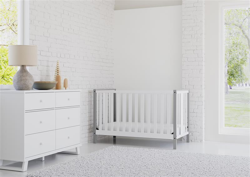 white crib with pebble gray angled in nursery with 6 drawer dresser