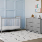 white crib with pebble gray in nursery with 6 drawer chest