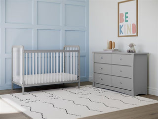 white crib with pebble gray in nursery with 6 drawer chest