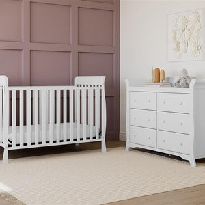 White crib in nursery with 6 drawer dresser
