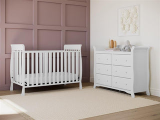 White crib in nursery with 6 drawer dresser