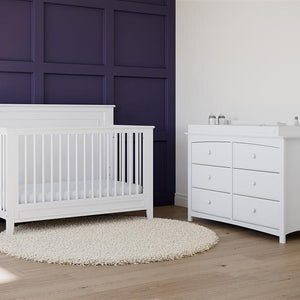 White crib in nursery with 6 drawer dresser 