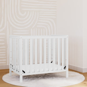 white mini crib in nursery
