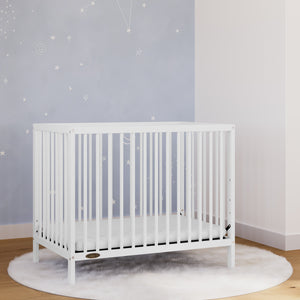 White mini crib in nursery