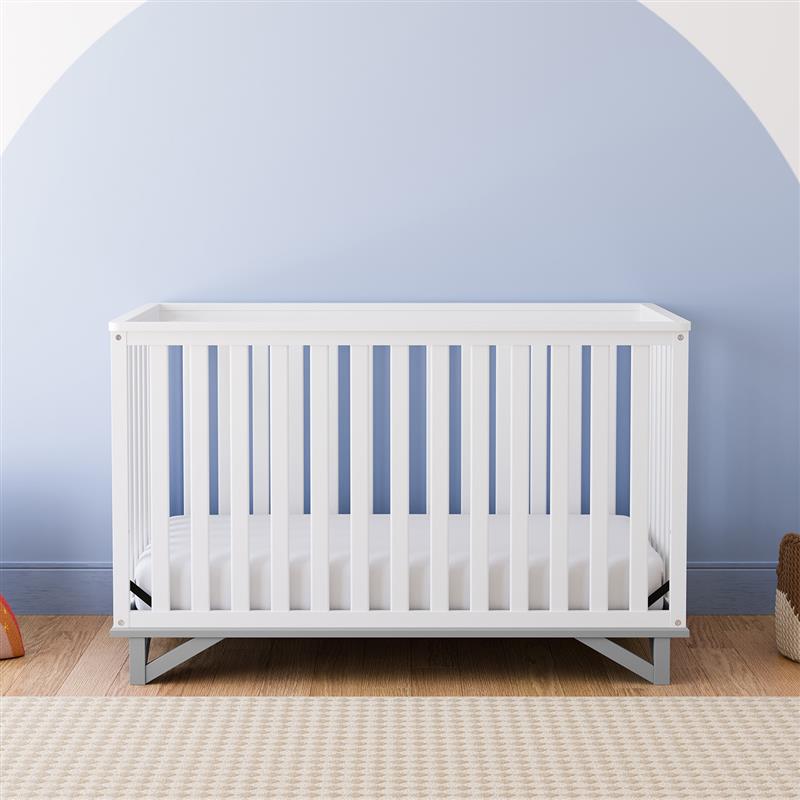 Front view of white crib with pebble gray in nursery
