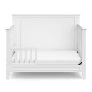 White crib in toddler bed conversion with one safety guardrail 