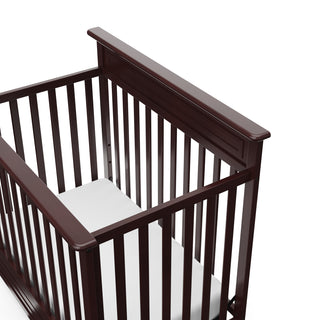 Close-up view of espresso mini crib's headboard 