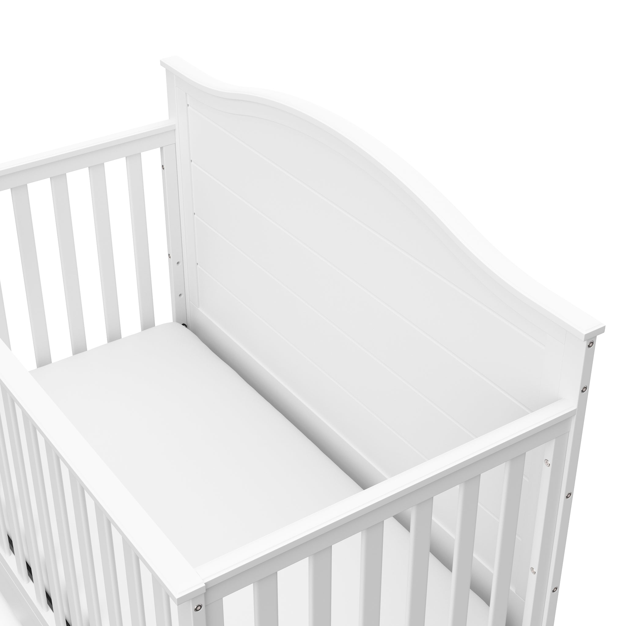 Close-up view of white crib with drawer headboard