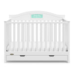 Front view of white crib with drawer