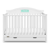 Front view of white crib with drawer