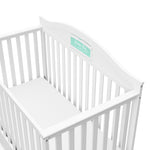 Close-up view of white crib with drawer