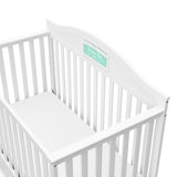 Close-up view of white crib with drawer