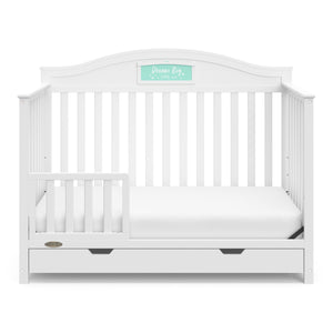 White crib with drawer in toddler bed conversion with one safety guardrail